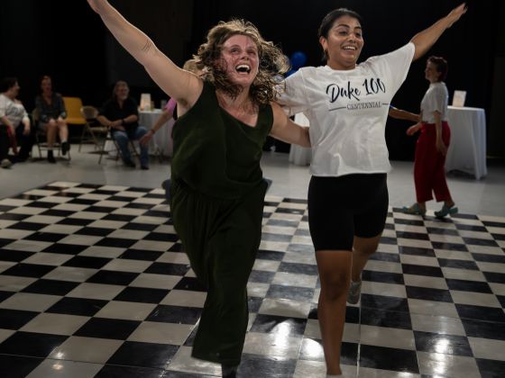 Two dancers laugh on the checkered dance floor of the Ark's dance studio