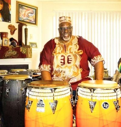 Bradley Simmons, standing next to two large drums, smiles at the camera