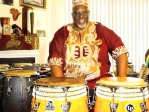 Bradley Simmons, standing next to two large drums, smiles at the camera